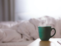 Tasse mit Warmgetränk vor Bett